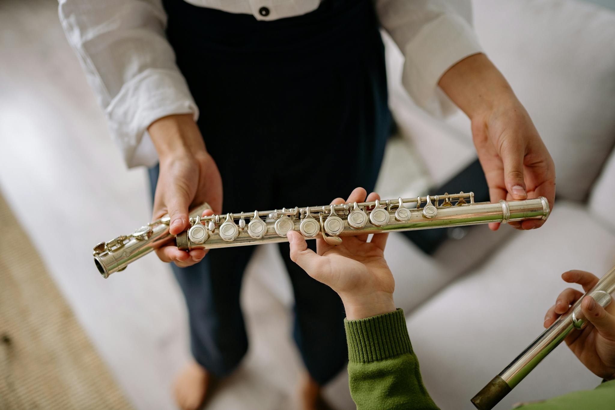 Teacher guiding child with flute playing, focusing on hands and instrument.